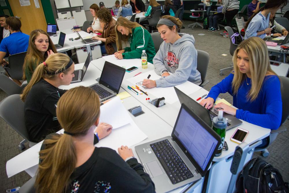 在这张2015年的照片中，学生们一边使用他们的西北笔记本电脑，一边在戈登大厅的新“模型教室”里利用技术. 